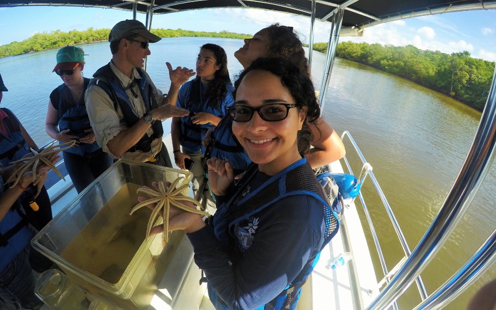 REU student holding a starfish on a boat